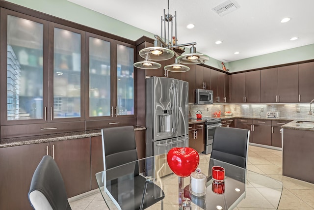 9068 Clearhill Rd, Boynton Beach, FL 33473 - kitchen featuring tasteful backsplash, dark brown cabinets, light stone countertops, visible vents, and appliances with stainless steel finishes