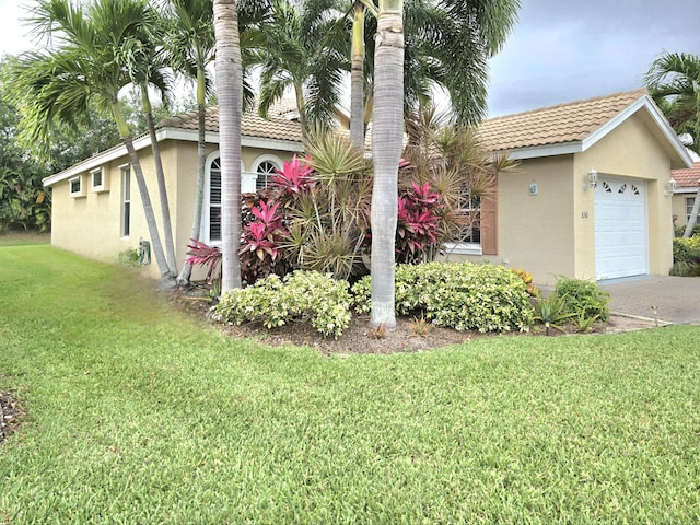 630 SW Treasure Cv, Port Saint Lucie, FL 34953 - view of front of property with a garage, a front lawn, stucco siding, a tiled roof, and driveway