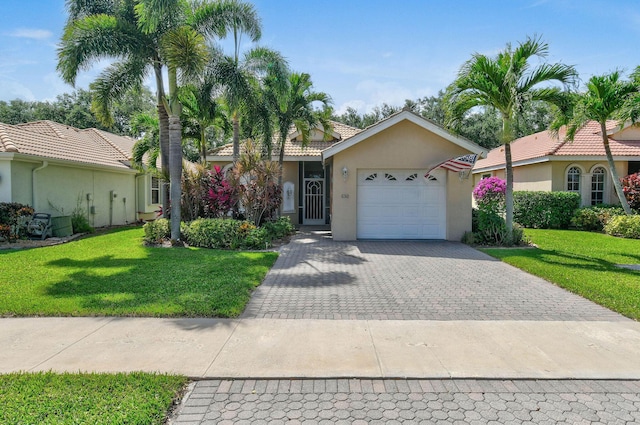 630 SW Treasure Cv, Port Saint Lucie, FL 34953 - ranch-style house with a tiled roof, decorative driveway, a front lawn, an attached garage, and stucco siding