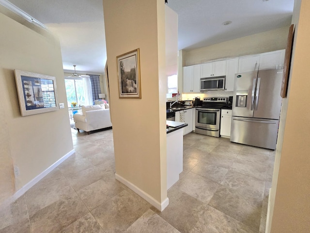 630 SW Treasure Cv, Port Saint Lucie, FL 34953 - kitchen featuring dark countertops, baseboards, open floor plan, white cabinetry, and appliances with stainless steel finishes