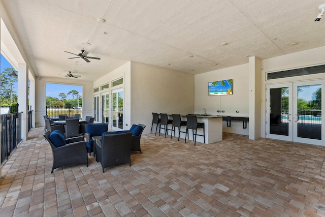 view of patio with outdoor dry bar, french doors, fence, and ceiling fan