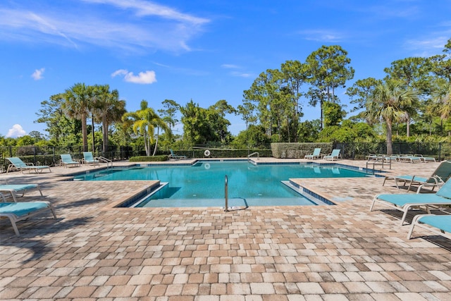 community pool with fence and a patio area