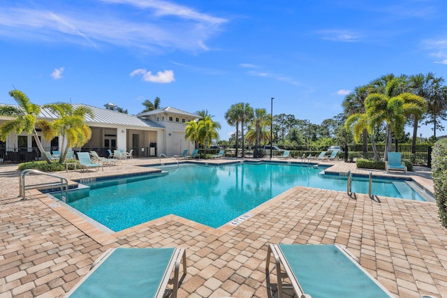 community pool with a patio and fence
