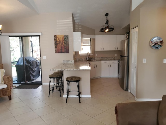 2831 Stoneway Ln Unit C, Fort Pierce, FL 34982 - kitchen featuring vaulted ceiling, a peninsula, freestanding refrigerator, light tile patterned flooring, and a sink
