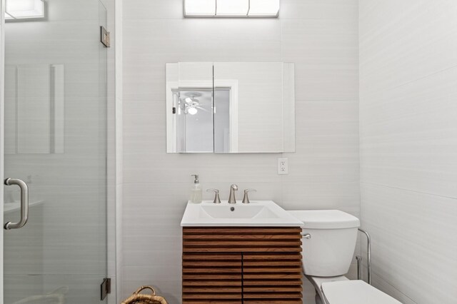 full bath with toilet, a stall shower, tile walls, and vanity