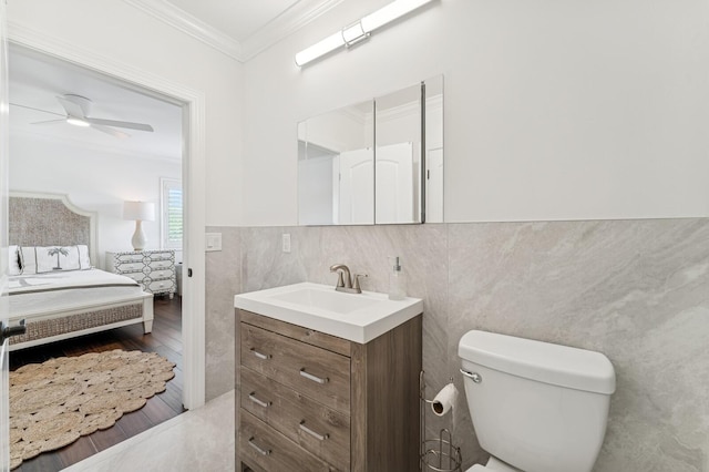 bathroom with tile walls, vanity, toilet, ornamental molding, and wood finished floors