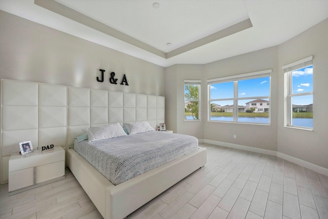 15649 Orchard Dr, Westlake, FL 33470 - bedroom featuring a water view, light wood-style floors, baseboards, and a raised ceiling