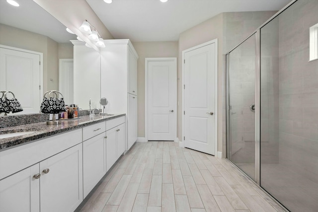 15649 Orchard Dr, Westlake, FL 33470 - bathroom with baseboards, a sink, a shower stall, double vanity, and wood finished floors