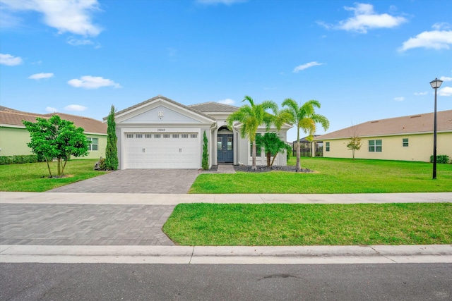 15649 Orchard Dr, Westlake, FL 33470 - ranch-style home with an attached garage, stucco siding, a front lawn, and decorative driveway