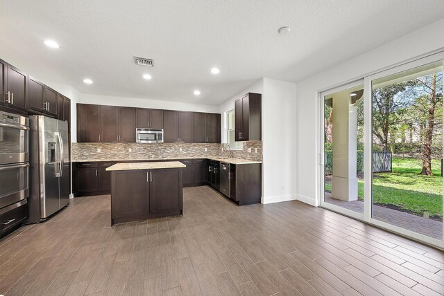 122 Diamante Way, Jupiter, FL 33477 - kitchen featuring stainless steel appliances, light countertops, dark brown cabinets, tasteful backsplash, and a kitchen island