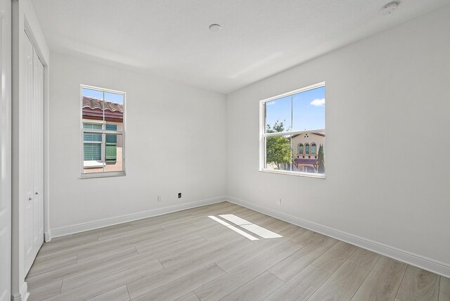 122 Diamante Way, Jupiter, FL 33477 - empty room with light wood-style floors, plenty of natural light, baseboards, and a smoke detector