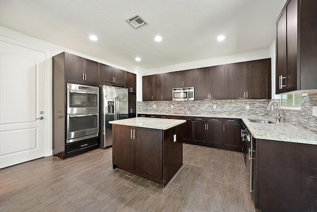 122 Diamante Way, Jupiter, FL 33477 - kitchen featuring appliances with stainless steel finishes, decorative backsplash, a kitchen island, light stone counters, and recessed lighting