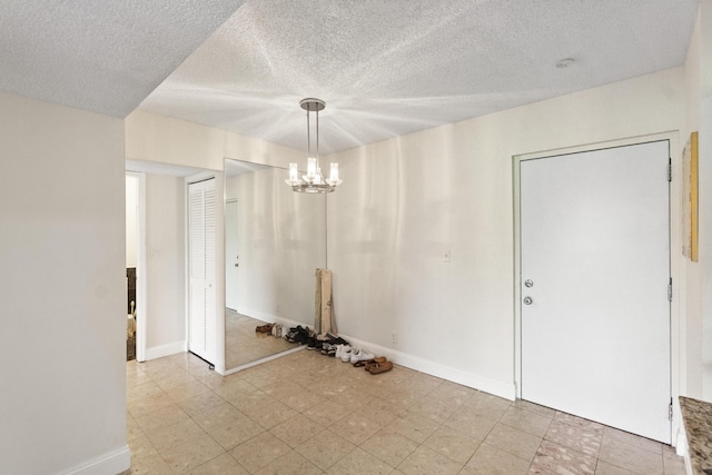 unfurnished dining area featuring a textured ceiling, an inviting chandelier, and baseboards