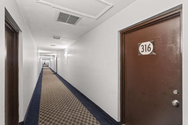 hall featuring visible vents, baseboards, and carpet floors