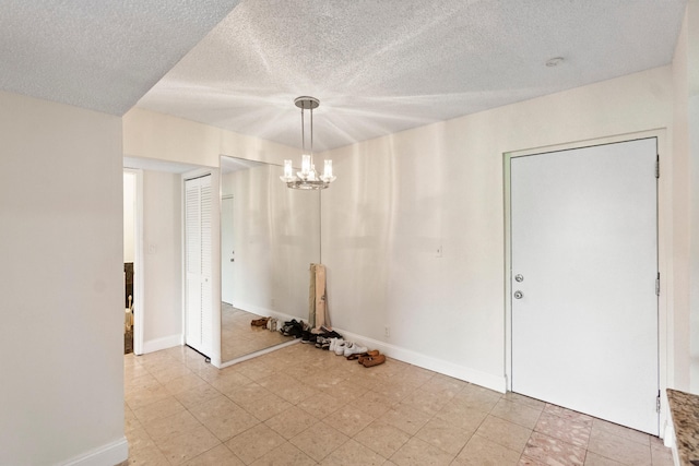 unfurnished dining area featuring a notable chandelier, baseboards, and a textured ceiling