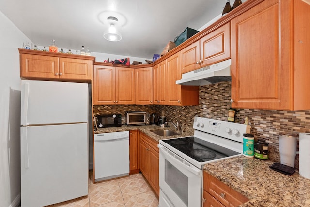 kitchen with a sink, tasteful backsplash, white appliances, and under cabinet range hood