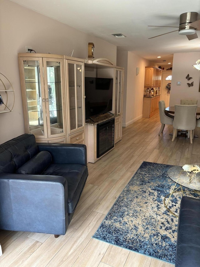 living area featuring light wood-style flooring, ceiling fan, baseboards, and visible vents