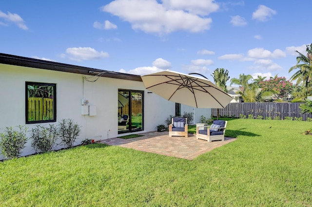 rear view of property with a yard, a patio, stucco siding, and fence