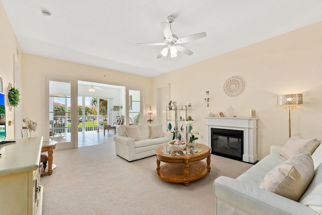 living room with a glass covered fireplace, light carpet, and ceiling fan