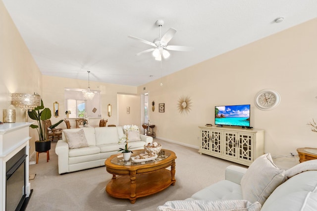 living room with baseboards, light colored carpet, and ceiling fan with notable chandelier