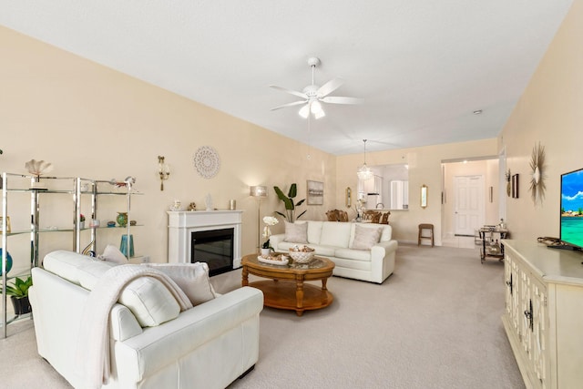 living area featuring light carpet, a ceiling fan, and a glass covered fireplace