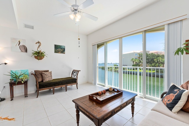 living room featuring a ceiling fan, visible vents, a water view, and light tile patterned floors