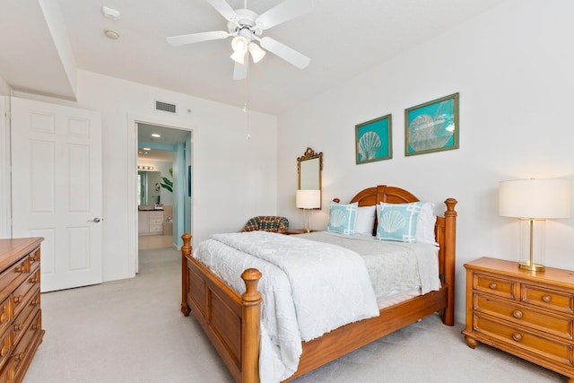 bedroom with visible vents, a ceiling fan, light colored carpet, and ensuite bathroom