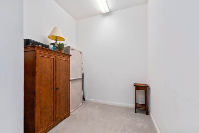 spare room featuring baseboards, a textured ceiling, and light colored carpet