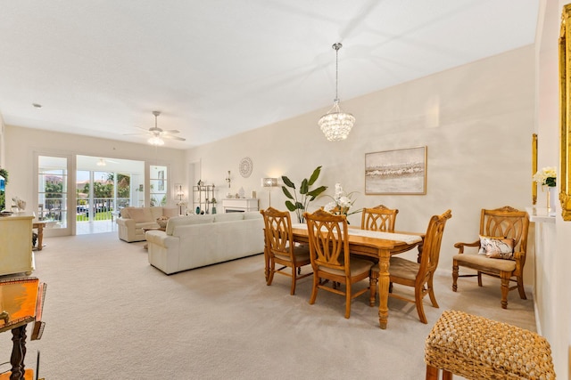 dining space with light colored carpet and ceiling fan with notable chandelier