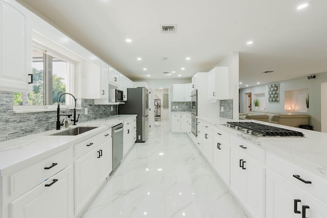 kitchen featuring light stone countertops, recessed lighting, a sink, decorative backsplash, and appliances with stainless steel finishes