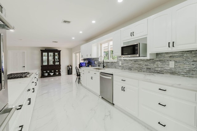 kitchen with light stone countertops, visible vents, a sink, decorative backsplash, and appliances with stainless steel finishes