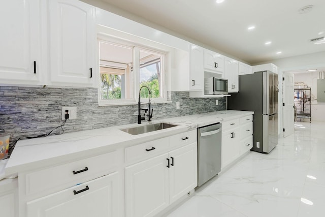 kitchen with marble finish floor, a sink, backsplash, appliances with stainless steel finishes, and light stone counters