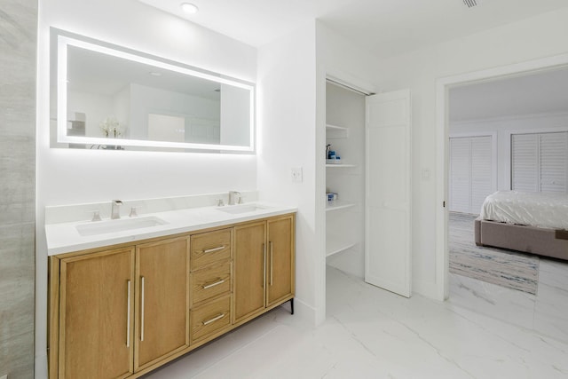 full bathroom with marble finish floor, double vanity, and a sink