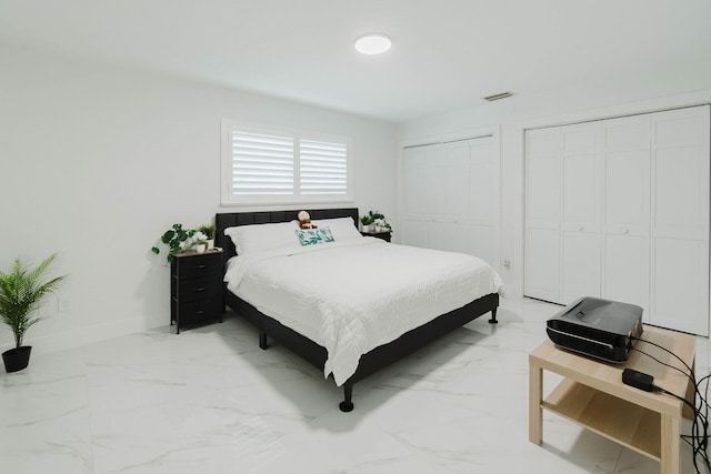 bedroom featuring baseboards, marble finish floor, multiple closets, and visible vents