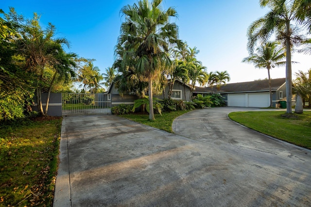 view of front of property featuring a front lawn, driveway, a garage, and a gate