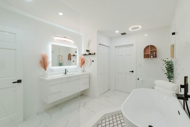 full bath featuring baseboards, a freestanding tub, marble finish floor, vanity, and recessed lighting
