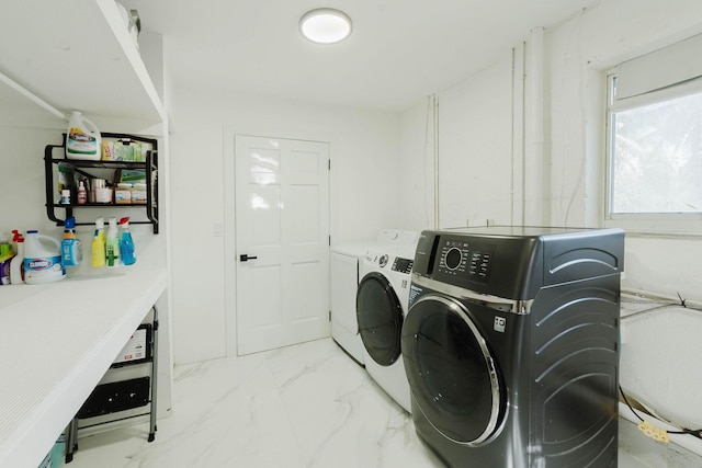 laundry room featuring marble finish floor, laundry area, and washer and dryer