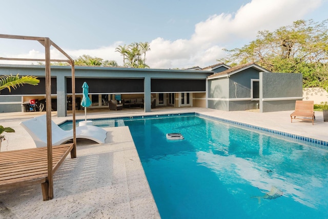 pool featuring a sunroom, outdoor lounge area, and a patio area