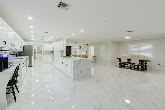 kitchen with stainless steel appliances, visible vents, light stone countertops, and recessed lighting