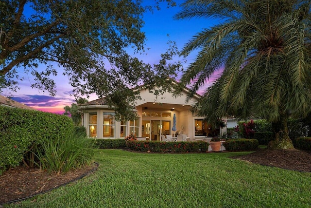 rear view of house with a lawn and stucco siding