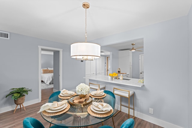 dining room featuring baseboards, wood finished floors, ceiling fan, and a chandelier