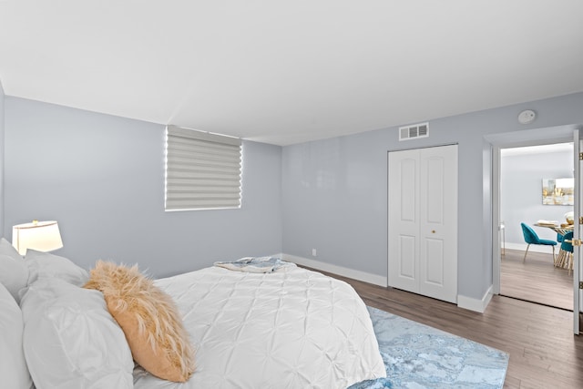 bedroom with wood finished floors, baseboards, and a closet