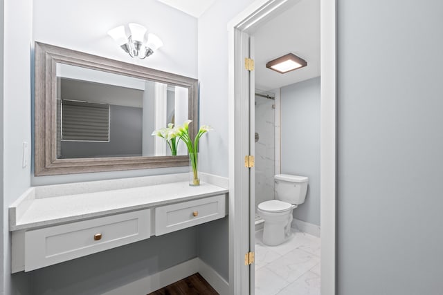 bathroom featuring toilet, a shower, marble finish floors, and baseboards