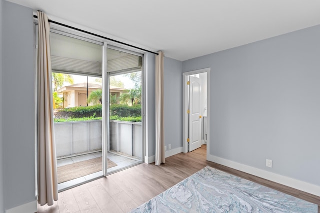 unfurnished bedroom featuring access to exterior, wood finished floors, and baseboards