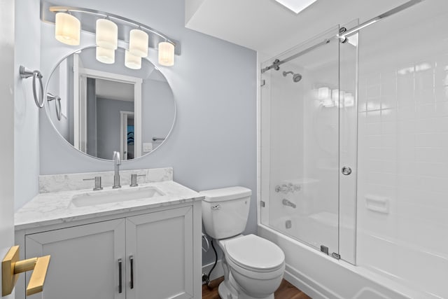 bathroom featuring toilet, vanity, shower / bath combination with glass door, and wood finished floors