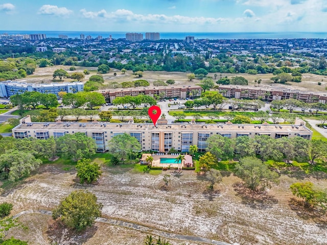 bird's eye view of apartment complex, a nearby body of water, and a pool area