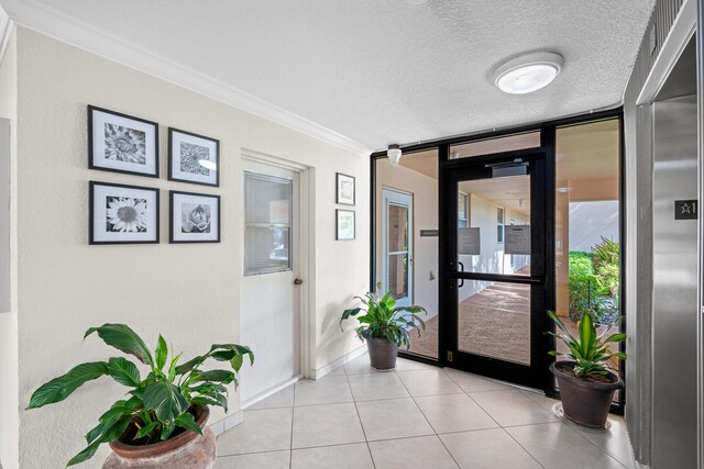 doorway to outside with ornamental molding, baseboards, light tile patterned flooring, a textured ceiling, and a wall of windows