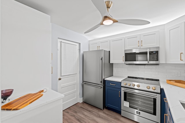 kitchen featuring stainless steel appliances, blue cabinets, backsplash, light wood finished floors, and light stone counters