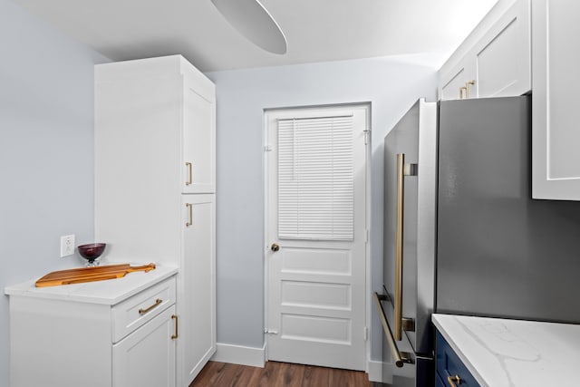 kitchen featuring freestanding refrigerator, dark wood-style floors, white cabinetry, light stone countertops, and baseboards