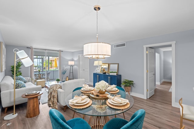 dining area featuring a chandelier, wood finished floors, and baseboards
